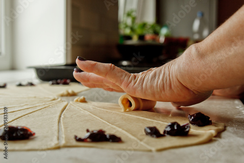 Sliced raw mixed dough with berries lies on the baking tray. cooking baking dish. women's hands roll the dough on a bagel