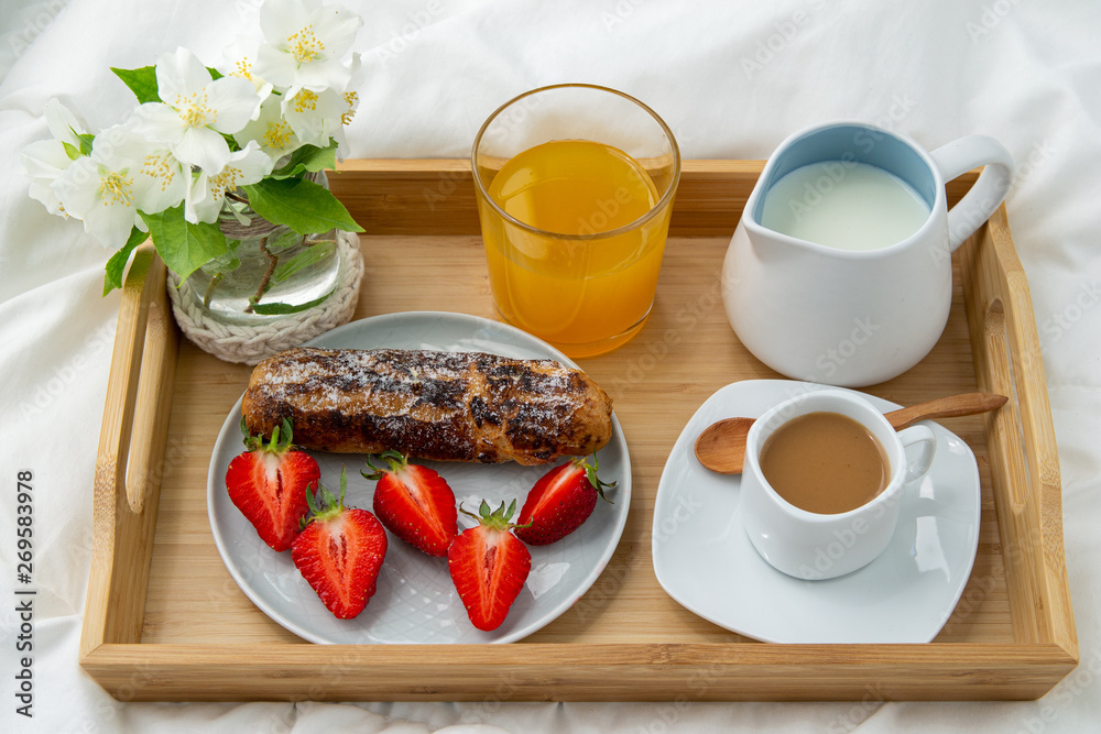Breakfast in bed. Wooden tray with coffee,orange juice, strawberries and Eclair . Jewelry with delicate white flowers.