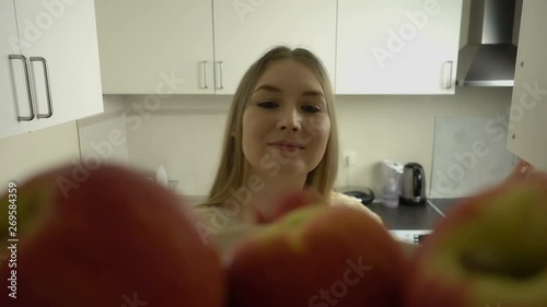 POV of attractive blonde hair young woman opens a cupboard and takes apple from a shelf. Healthy lifestyle.