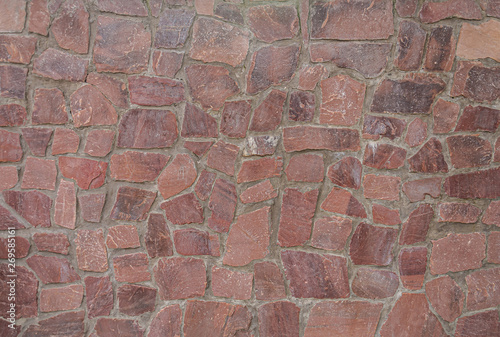 Powerful reliable wall (fence) from a large red granite stone.