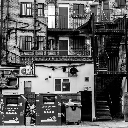 External Facade of Old Buidings with Fire Escapes and Waste or Rubbish Wheely Bins photo