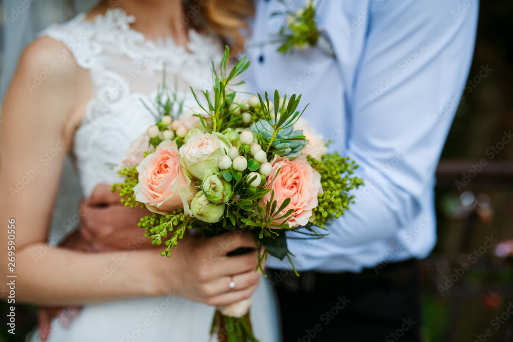 Bridal bouquet in the hands of the newlyweds