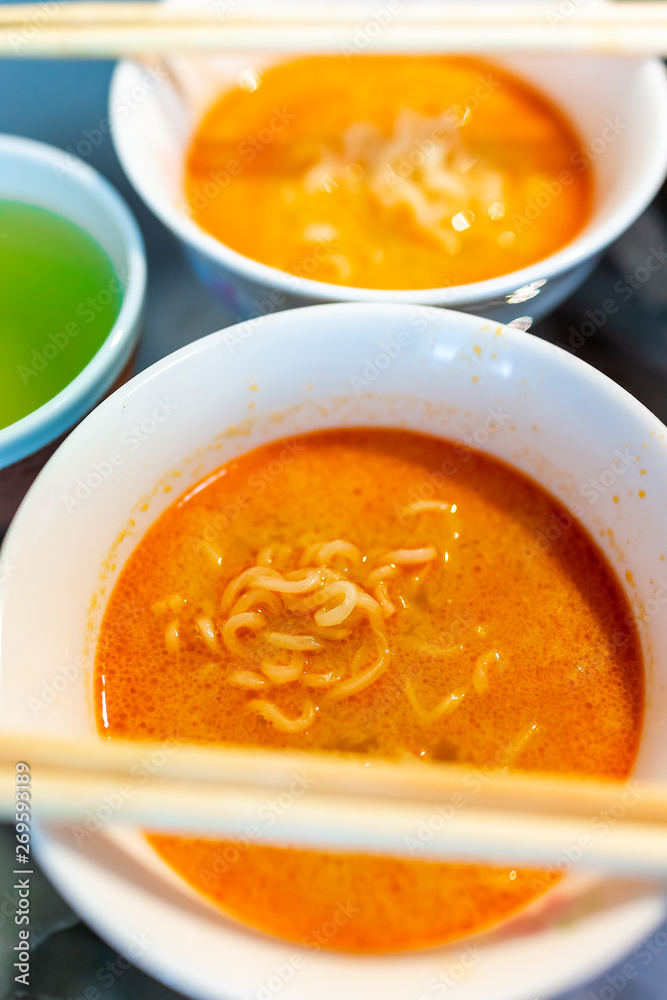 Macro closeup of spicy red ramen noodle soup bowl with chopsticks Japanese asian meal and green tea Macro closeup of spicy red ramen noodle soup bowl with chopsticks Japanese asian meal and green tea