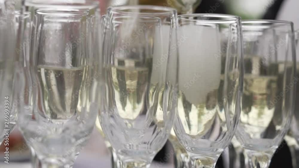 Champagne is poured into glasses. Closeup of a bottle of champagne. Champagne is poured into glasses. Closeup of a bottle of champagne.