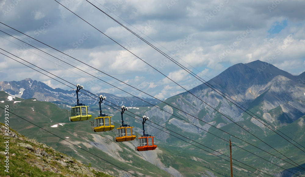 Empty gondola lift runs up the rocky mountain in the spectacular French Alps.