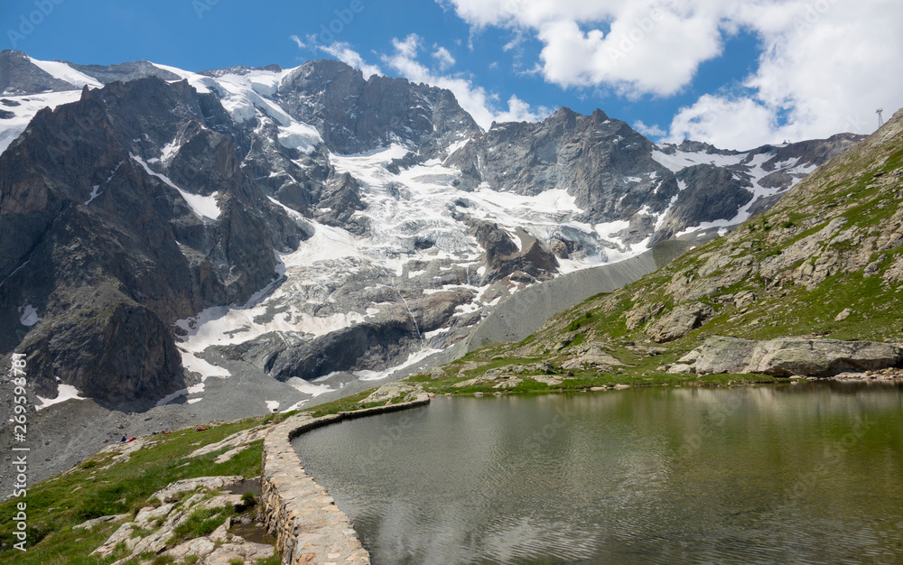 Breathtaking view of the snowy mountain range behind an artificial lake in Alps.