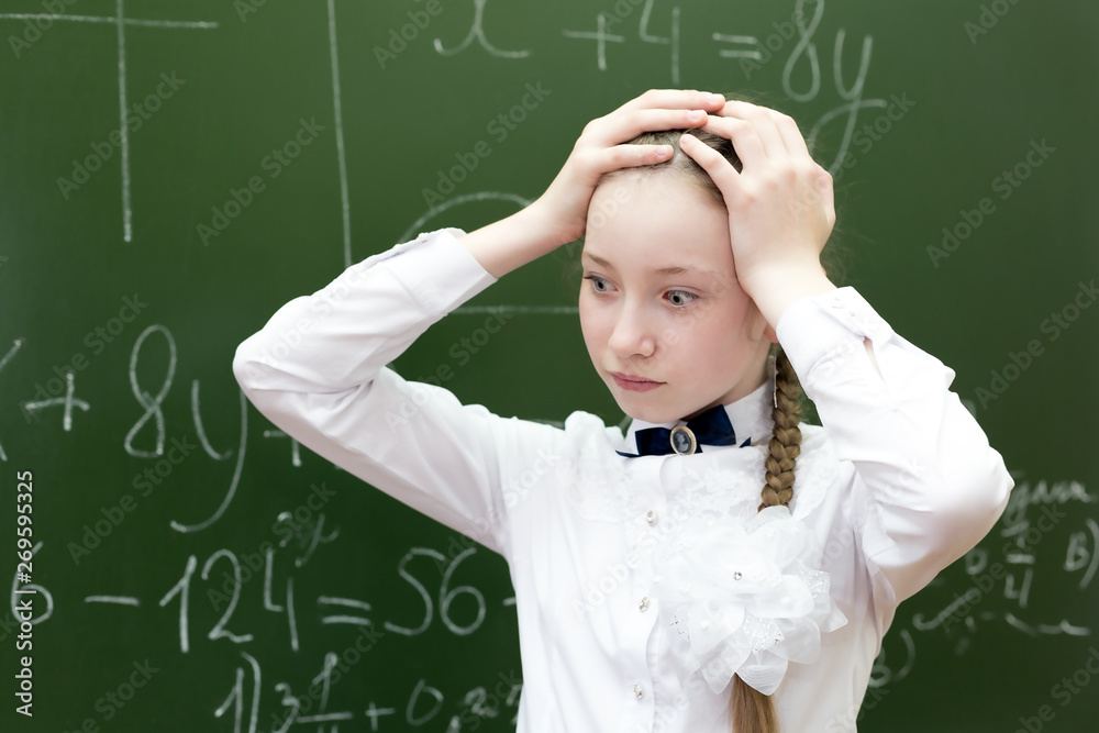 Girl student holding her hands over her head tension fatigue, the solution of a difficult task in mathematics. schoolgirl grabbed her head from the tension.