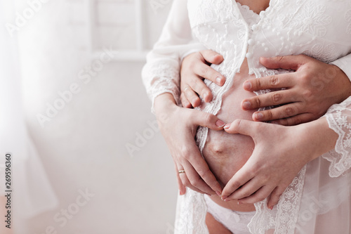 uture parents. hands of future mom and dad on the belly of a pregnant woman.