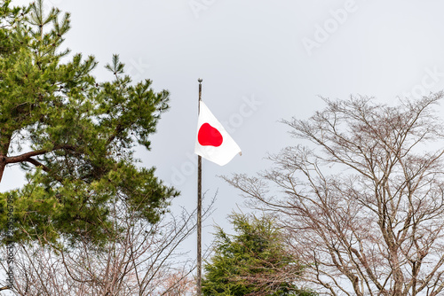 Takayama, Japan Hida no Sato old folk village closeup of Japanese red and white flag isolated against sky on flagpole pole