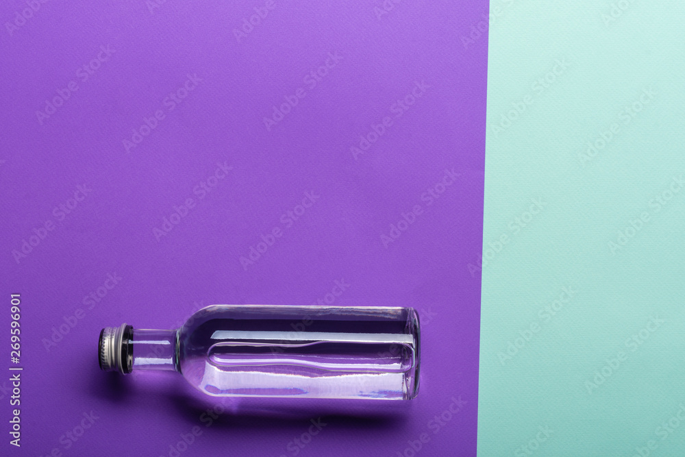 glass bottle with water on bright purple and azure background glass bottle with water on bright purple and azure background