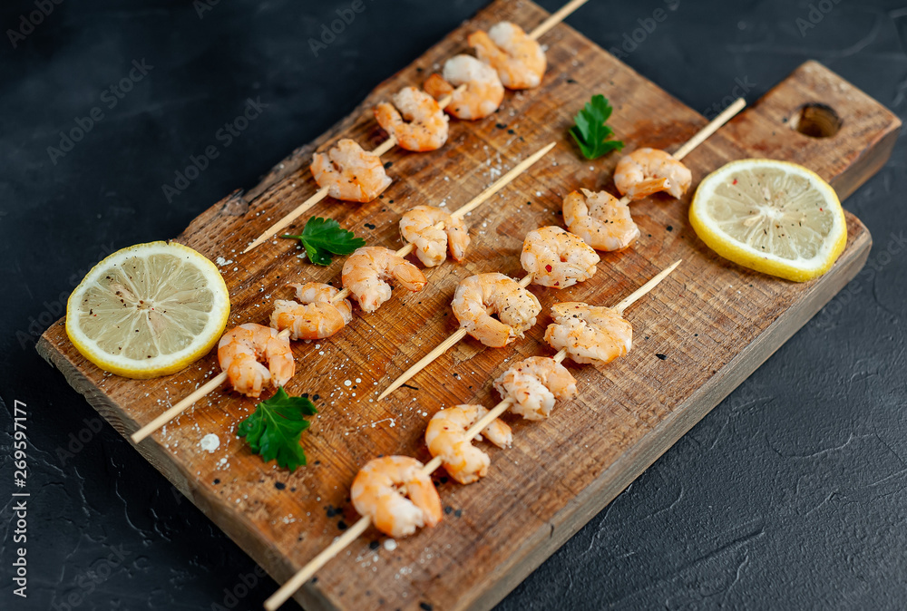 Grilled shrimp shashlik. shrimps with parsley and lemon on the background of concrete