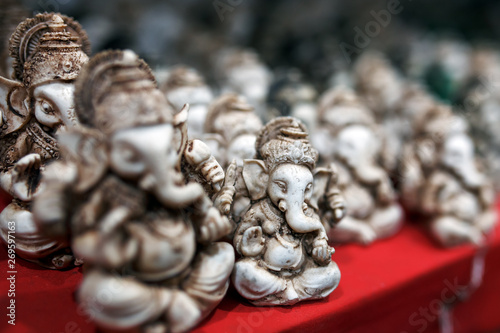The stone statuette of Ganesh is green, contrasting with the group of light Ganesh on the counter of the Indian market © Alexander