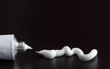 tube of white cream, ointment stroke squeezed out on black background