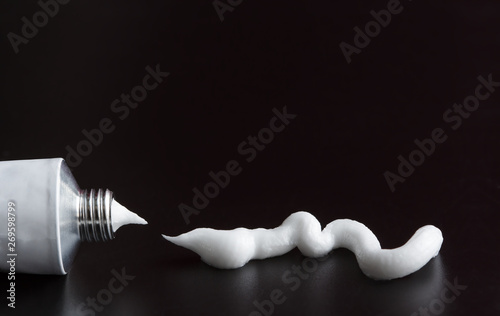 tube of white cream, ointment stroke squeezed out on black background photo