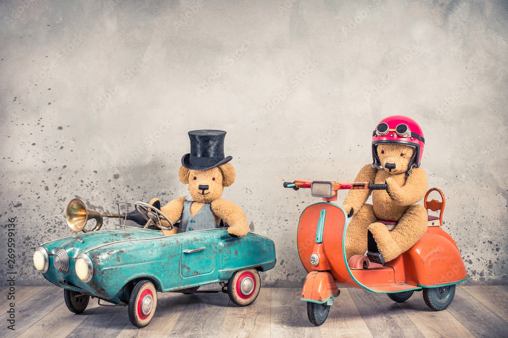 Fotka „Teddy Bear in antique cylinder hat driving rusty retro toy pedal car  from circa 60s and Teddy Bear in red helmet with goggles sitting on old  orange children's scooter. Vintage style