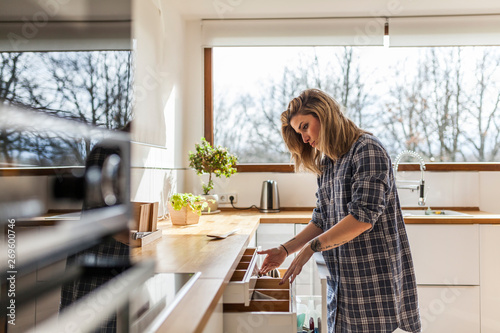 Blond young woman working in kitchen at home photo