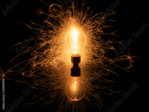 Light bulb with sparklers from behind on black background photo