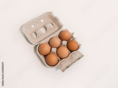 Six eggs in carton on white background, top down view from above.