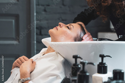 Stylist washing hairs to young lady photo