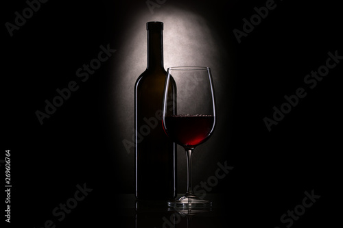 Still-life with the wine glass, red wine in a glass near to a bottle