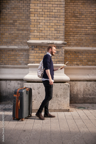 one man - traveler or tourising, finding his way with a city map, on a street. photo