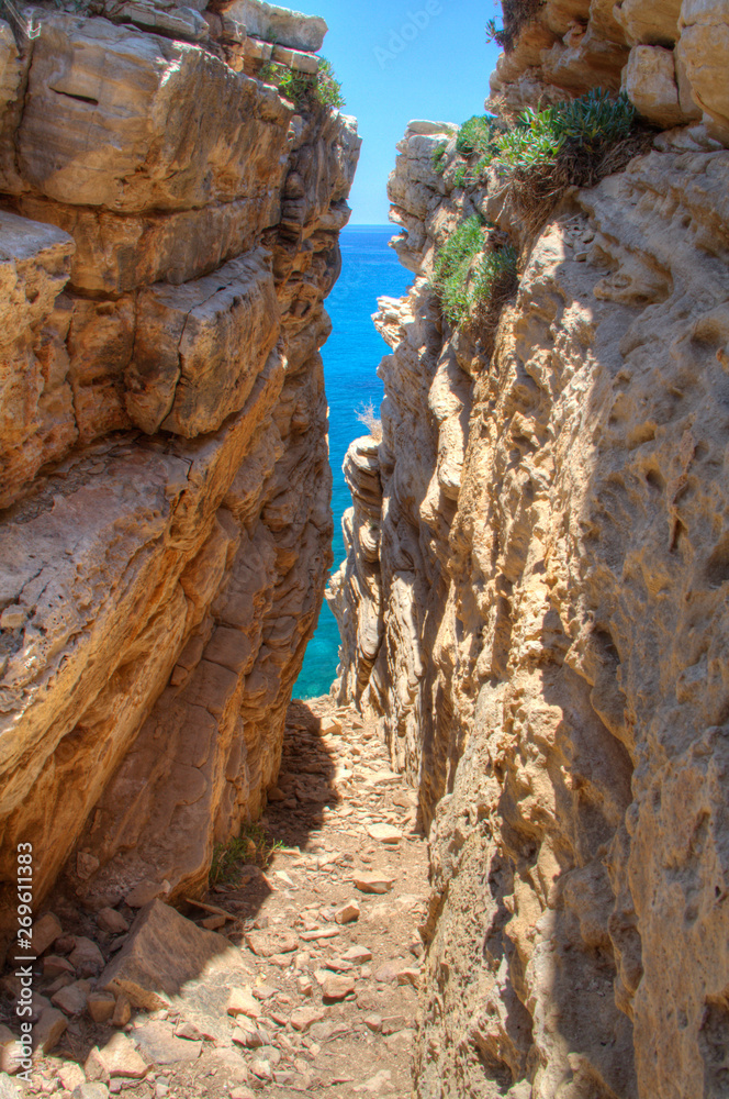 Looking through a narrow cave at the blue sea and sky