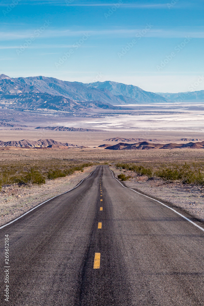 Looking down a road leading into Death Valley in California, with salt flats and a vast landscape ahead