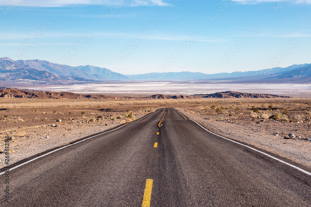 Looking down a road leading into Death Valley in California, with salt flats and a vast landscape ahead Looking down a road leading into Death Valley in California, with salt flats and a vast landscape ahead