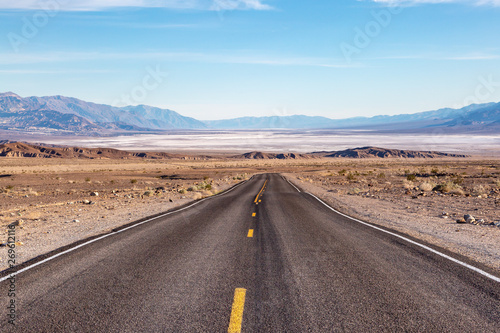 Looking down a road leading into Death Valley in California, with salt flats and a vast landscape ahead photo