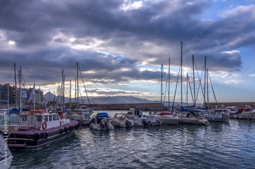 Heraklion, Crete Island - Greece. View to the old Venetian port in Heraklion city full of fishing boats and yachts. Cloudy sky