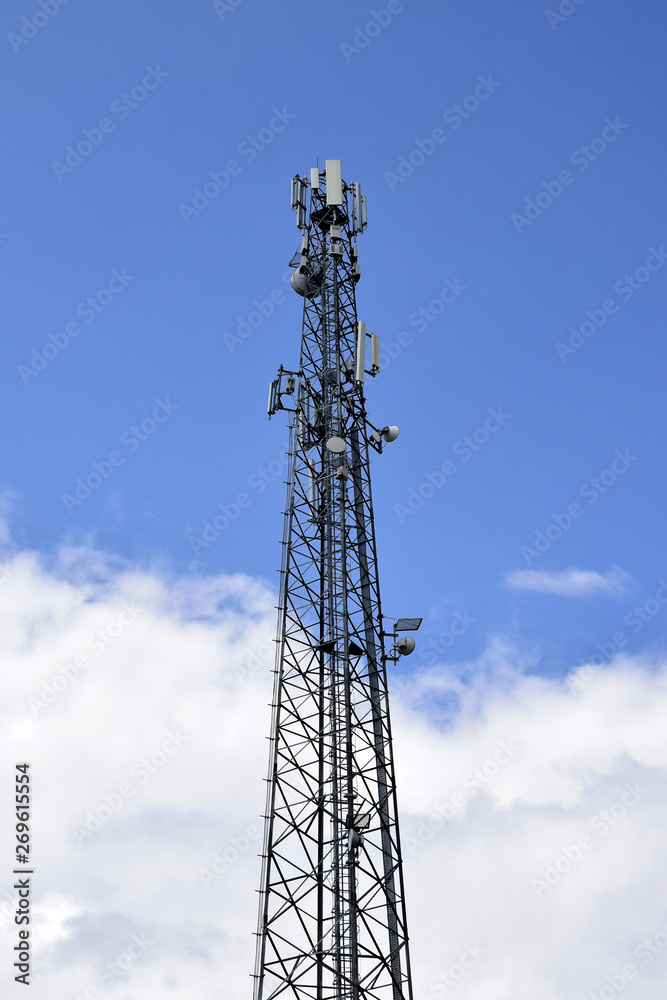 Cell tower against blue sky with clouds. A cell site or tower with antennae and telecommunications equipment is part of cellular network. Wireless communication. Moldova. Selective focus. Copy space.