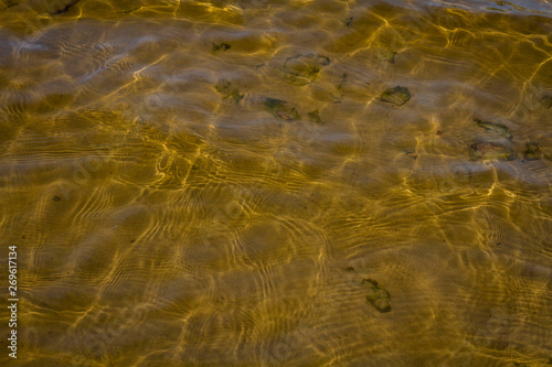 the sand and stones under water with the waves in the foreground .
