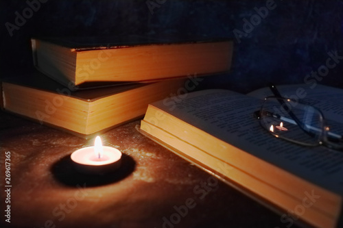 Lighted candles in an intimate setting, old books, yellowed from time to time, glasses in a knitted yellow thread.