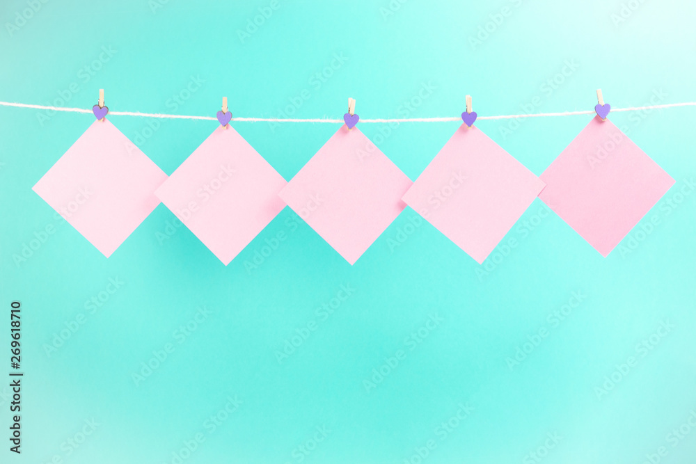 Pink stickers on clothesline with clothespins isolated on blue background. Place for your text.