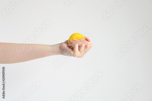 Hand pressing yellow squishy ball for exercise muscle or for feeling relax from stress; concept of health care and medical. photo