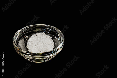 A pinch of salt in a small, bowl on a black background.