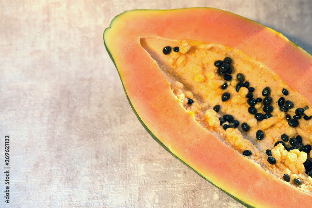 Papaya (Carica papaya) is an exotic, tasty, sweet fruit. Melon (bread) tree fruit against a pink background. Half. Papaya seeds are edible and can be a cure. Close-up. Papaya (Carica papaya) is an exotic, tasty, sweet fruit. Melon (bread) tree fruit against a pink background. Half. Papaya seeds are edible and can be a cure. Close-up.