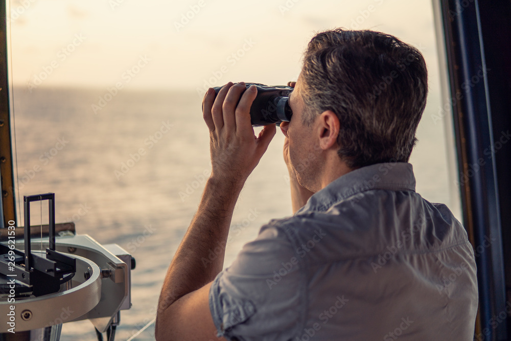 Navigational officer lookout on navigation watch looking through binoculars. Marine industry. COLREG collision regulations