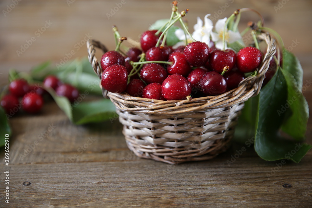 fresh organic sweet cherries in a wicker basket with leaves and white flowers on the wooden rustic background. Healthy food concept. Closeup. fresh organic sweet cherries in a wicker basket with leaves and white flowers on the wooden rustic background. Healthy food concept. Closeup.