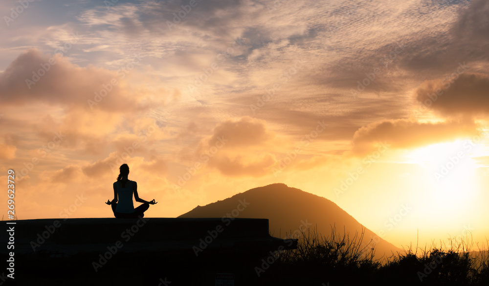 Peace and serenity. Female meditation outdoors on a mountain at sunset. 