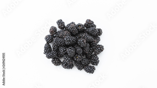 A wide angle of a pile of fresh lush blackberries laying on top on a white backdrop.