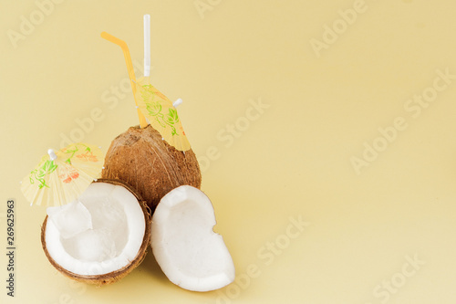 Fresh Coconut cocktail with a straws on yellow background, copy space