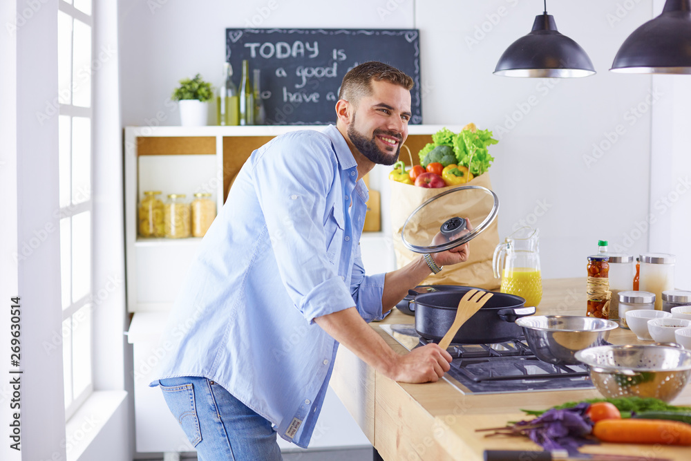 Smiling and confident chef standing in a large kitchen tasting Smiling and confident chef standing in a large kitchen tasting