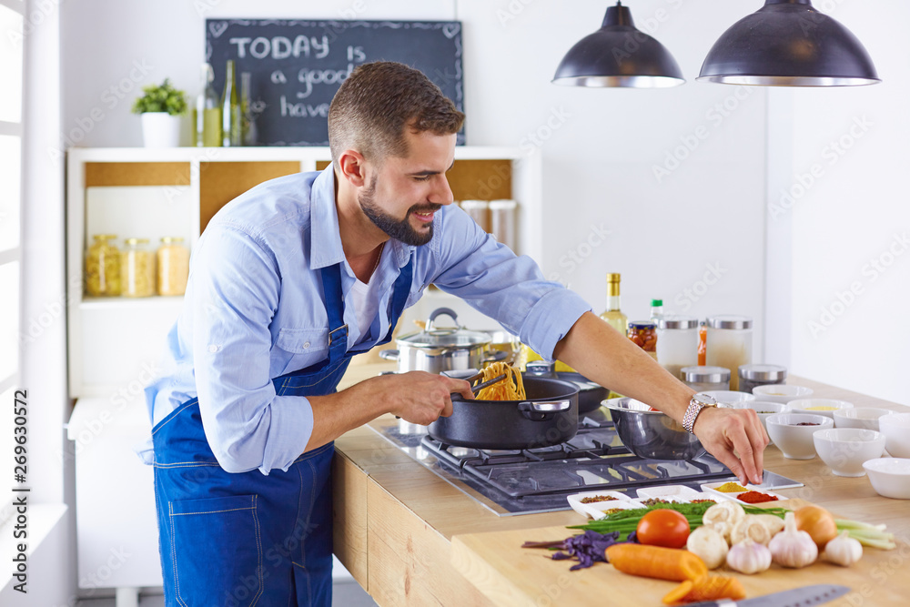 Smiling and confident chef standing in large kitchen Smiling and confident chef standing in large kitchen