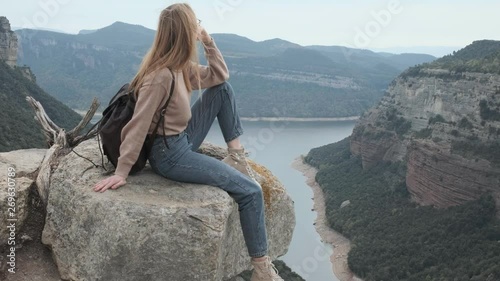 Video de stock  Girl sits on a rock overlooking the river and enjoys a magnificent view, gorge overlooking the blue lake