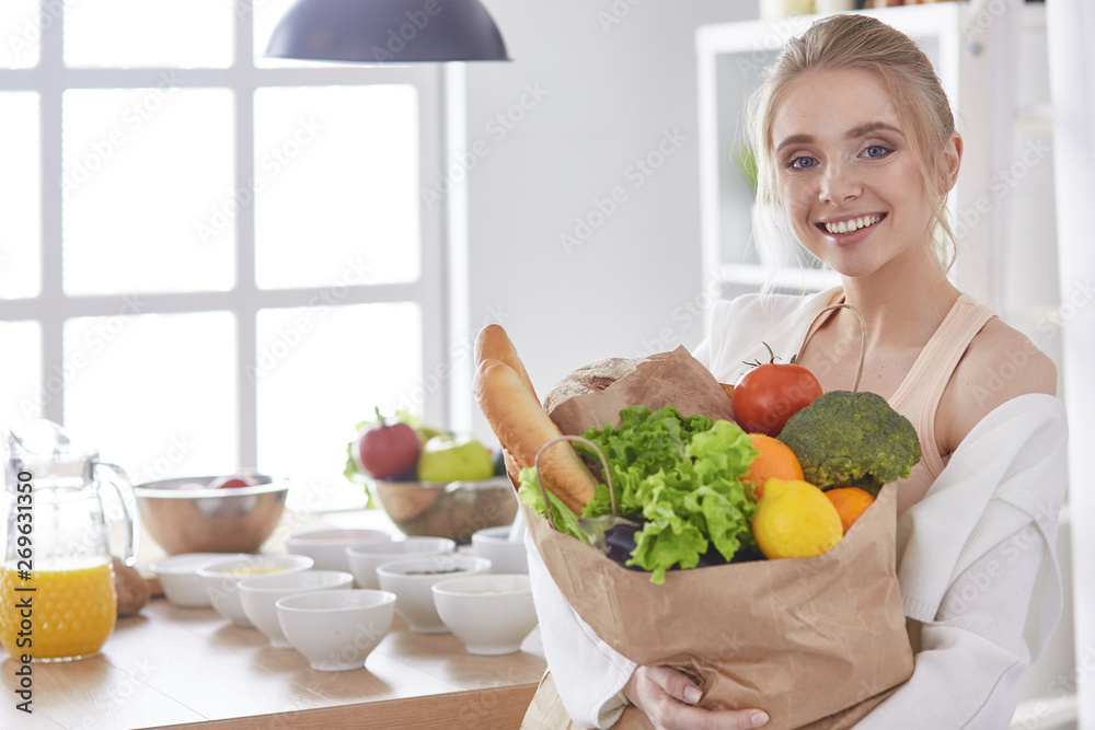 Young woman holding grocery shopping bag with vegetables Standi Young woman holding grocery shopping bag with vegetables Standi