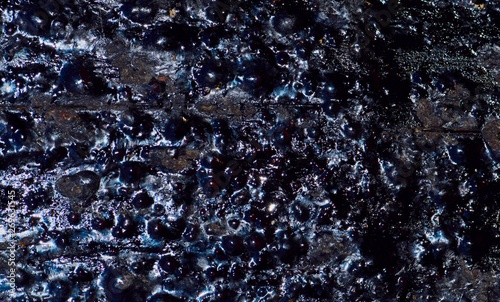 Close up of dried black tar on a wooden power pole with glossy rough textures.