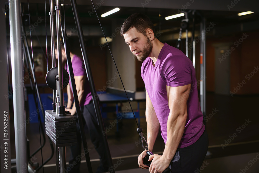 Young adult bodybuilder healthy fitness man doing triceps overhead extension rope exercise. Workout in public gym and sporty lifestyle concept Young adult bodybuilder healthy fitness man doing triceps overhead extension rope exercise. Workout in public gym and sporty lifestyle concept