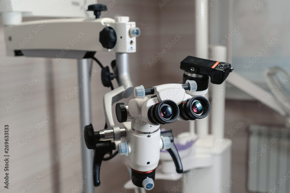 Dental binocular microscope on the background of modern dentistry. Medical equipment. operating microscope. with rotary double dental microscope white cabinet working room