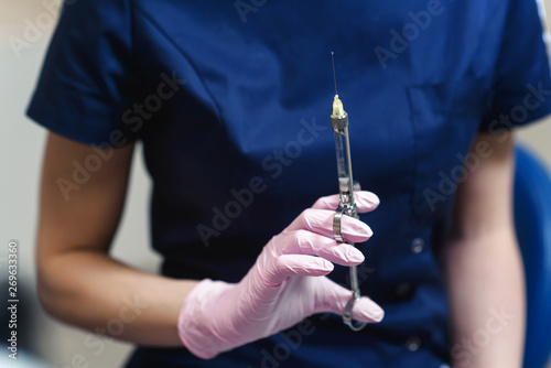 Doctor holding in her dentist's hand carpool syringe for local anesthesia on background isolated photo